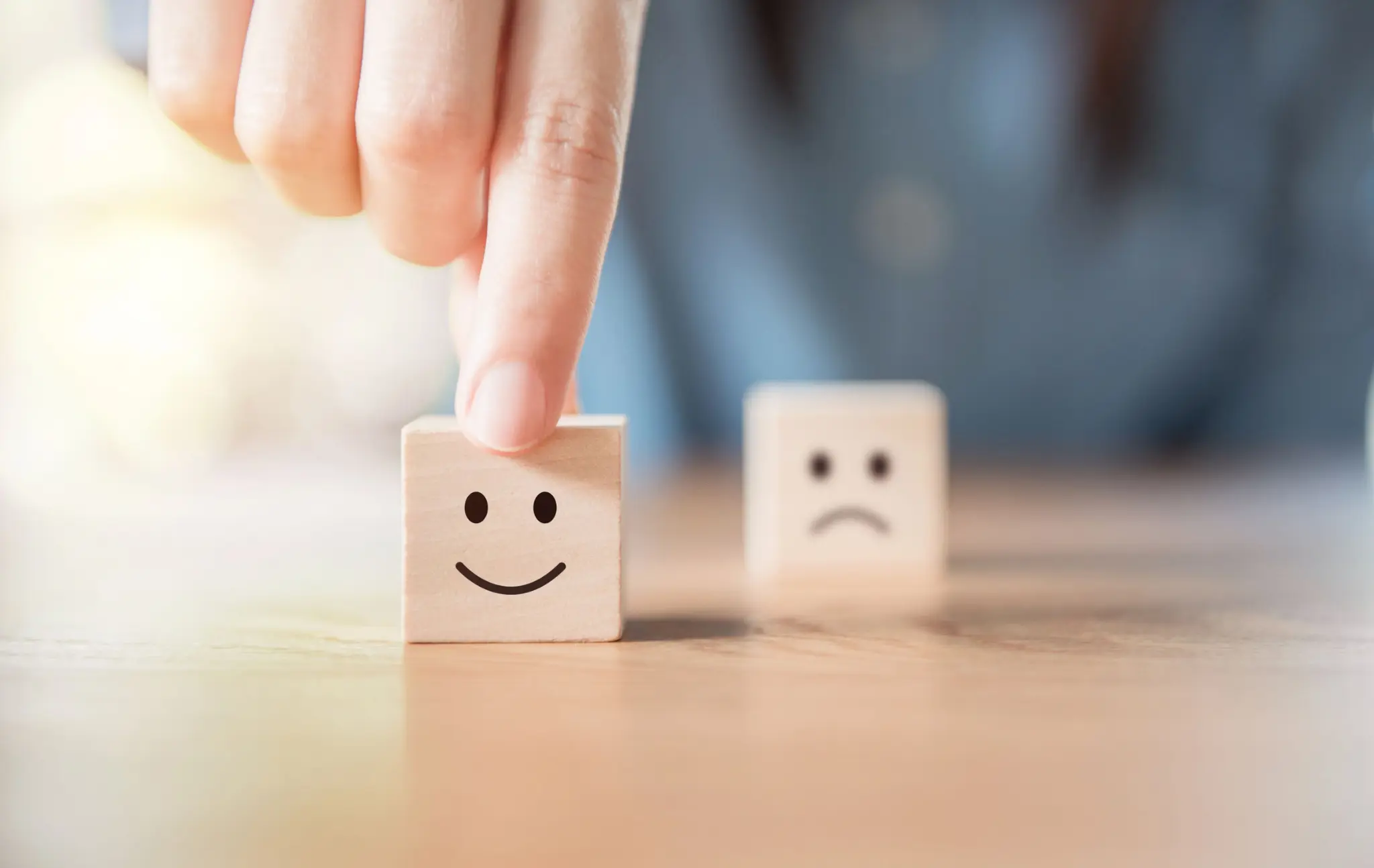 Würfel mit Smiley im Vordergrund, mit traurigem Blick im Hintergrund