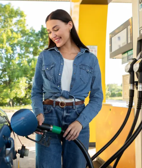 Lächelnde Frau tankt ihr Auto an Tankstelle